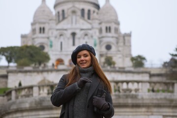 Fototapeta premium Smiling Beautiful Woman in Paris with Sacre Coeur Basilica in the Background