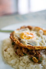 A plate of spicy basil stir fry with pork, topped with a crispy fried egg stunning presentation