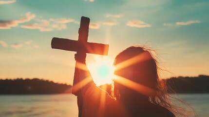Silhouette of a person holding a cross against a bright sunset, symbolizing faith and spirituality in nature.