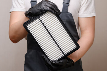 Man holding new car air filter in hands, close-up. Concept of auto parts replacement, air filter, car maintenance