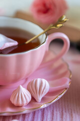 A cup of aromatic tea, a book and a rose on the table.