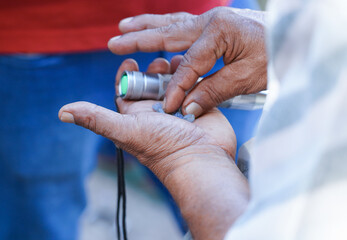 An individual at the Nivithigala gem market in Sri Lanka inspects rough gemstones using a Chinese...