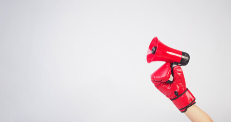 Hand is hold red megaphone and wear red boxing gloves on white background.