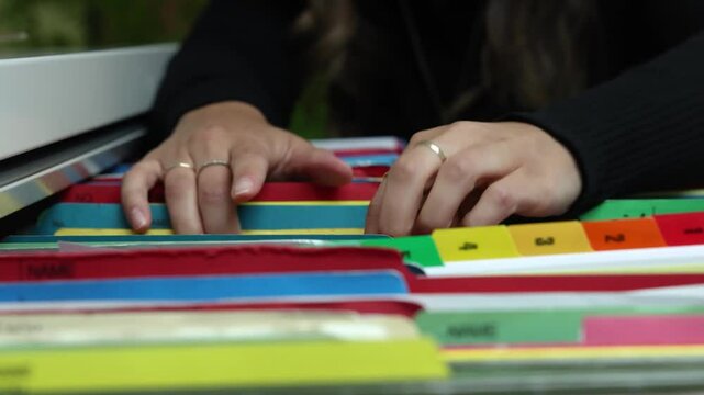 Secretary searching through files in a drawer, showcasing the process in slow motion within an office environment. Selective focus