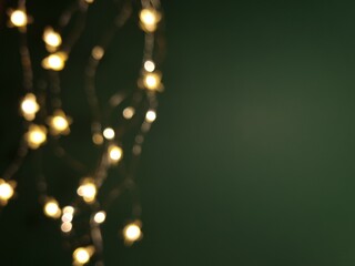Bright lights of electric garland on green background. Defocused
