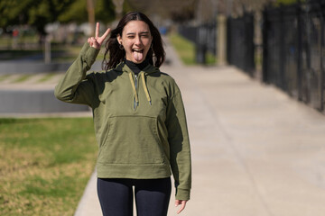 Young woman gesturing victory with her hand and tongue out