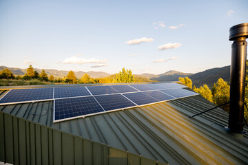 Solar panels on the roof of a house in the mountains during sunset. Clean energy technology blends...