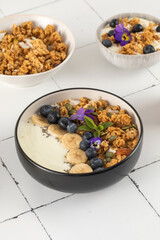A healthy nutritious breakfast of natural Greek yoghurts, granola and fresh berries on tile background.