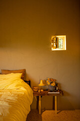 Softly lit bedroom with a warm yellow palette, highlighting a cozy bed and minimalist decor. A...