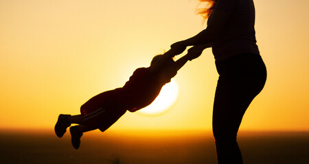 mom holding son hand walking in field silhouette at sunset in nature. happy family walking on nature, lifestyle concept