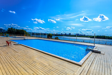 Blue swimming pool landscape with the wooden floor at the city for rest.