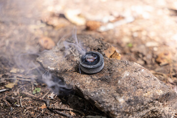 Resin incense burning on a rock, releasing fragrant smoke into the natural environment. Selective focus