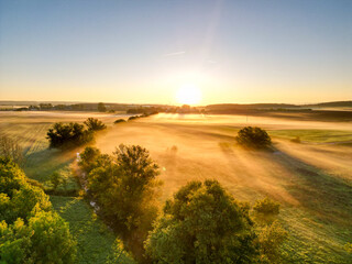 Sonnenaufgang über Schweinfurt mit Nebelschleiern, Nebel über den Feldern, mit einem Bach und...