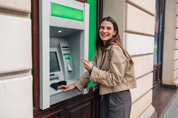Woman withdrawing cash from atm and smiling