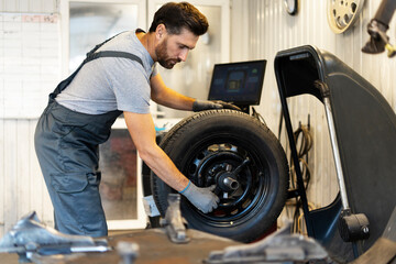 Mechanic mounting tire on wheel rim using professional equipment