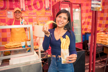 Latina girl shows the camera the delicious fried plantain slices she bought at the churros and plantain stand.