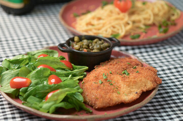 plate of food with chicken breast salad and caper sauce fish and chicken fillet
