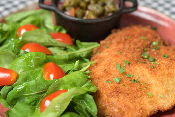 plate of food with chicken breast salad and caper sauce fish and chicken fillet