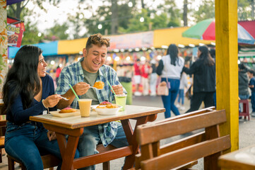 Two young Latinos enjoy their food at a street food stand.