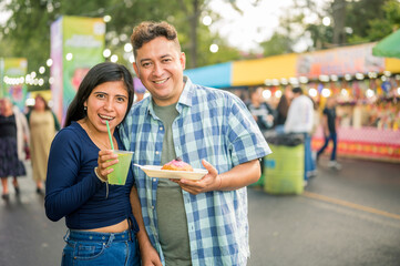 A couple of friends eat food while walking through the streets of their city with food stalls...