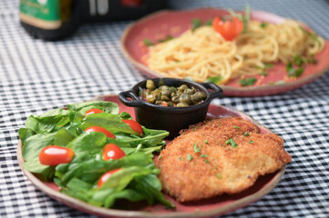 plate of food with chicken breast salad and caper sauce fish and chicken fillet