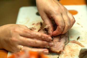 women's hands delicately extracting a fish bone, symbolizing care, culinary skills, and connection to nature. The image captures the essence of tradition and mindfulness in cooking