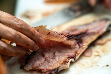 close-up of womens hands skillfully preparing fish, carefully filleting it. The image captures the essence of culinary art and tradition, highlighting expertise and the intimate relationship with food