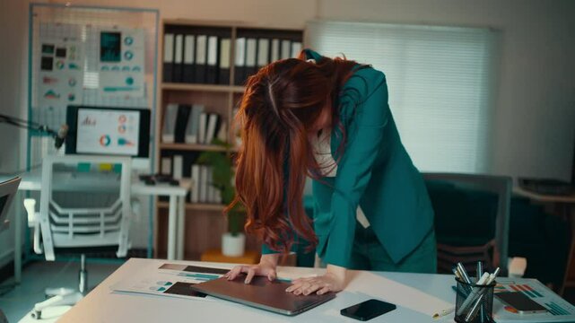 Young businesswoman wearing a suit is getting increasingly frustrated with her work, culminating in her slamming her laptop shut
