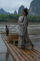 Hanfu Chinese girl with cormorants on a bamboo raft appearing a lantern. Slowmo