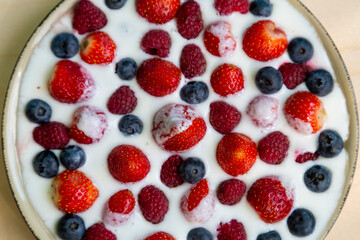 In a plate with freshly whipped cream juicy berries strawberries raspberries