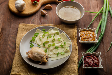 Dagestan khinkal homemade dough, meat, thick broth, garlic and greens and bowls with mustard and adjika on the table