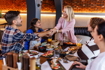 Family and friends gathered in a restaurant to eat delicious food, talk, drink and hang out.