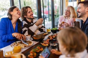 Family and friends gathered in a restaurant to eat delicious food, talk, drink and hang out.