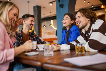 Group of friends hanging out at cafe, drinking coffee and orange juice.