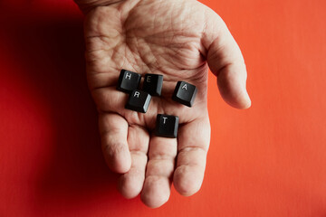 A hand holds computer keys that form the word "heart" with the letters H, E, A, R, T close-up, red background, the word "heart" from letters, long-distance relationships, hand and heart.
