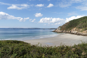Les falaises rocheuses se dressent autour de la plage de Trez Bihan, baignée par les eaux claires de la mer d’Iroise, dans la baie de Douarnenez. Le ciel bleu et les nuages apportent une touche de dou