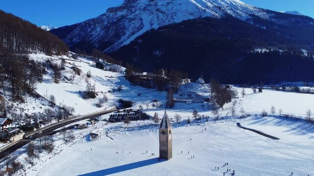 Winter on Lake Resia and magnificent isolated bell tower of the old village of Curon. Val Venosta