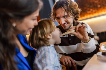 Family of three eating in a restaurant delicious food. Food and drink concept.