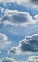 A photo of the sky with fluffy clouds against a bright blue backdrop. A tranquil atmosphere with light filtering through the clouds.