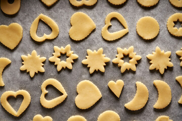 Shapes made of raw pastry dough on a sheet of baking paper - preparation of Linzer Christmas cookies