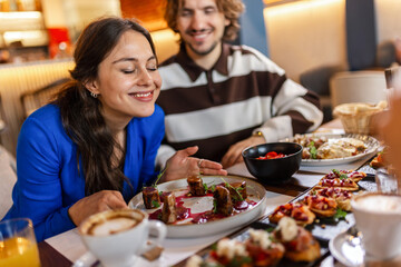 Couple in a restaurant eating delicious food. Girlfriend smelling the food. Food and drink concept.