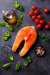 Salmon steak, fillet with herbs, tomatoes and spices. Dark background. Top view.
