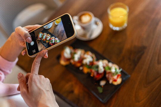 Woman influencer taking pictures of food in a restaurant. Social media. Food and drink concept.