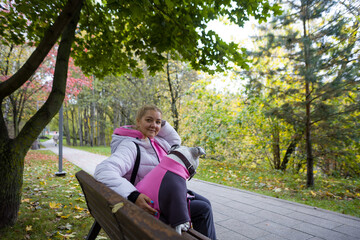 A woman walks a fashionable dog. A dog in a fashionable jacket and glasses, the owner and the dog...