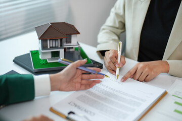 Real estate agent guiding client through home purchase contract. Discussing details in office...