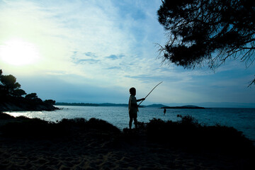 A happy child fishing by the sea silhouette