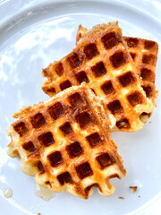 Golden waffle with honey on white plate.