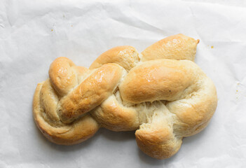 Overhead view of freshly baked challah on white parchment paper, top view of homemade braided challah, homemade challah baking fail