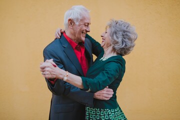 An Elderly Couple Dances Together: Joy and Love Shine as They Celebrate Life in a Retro Party Full of Fun and Happiness on Yellow Backgroun.