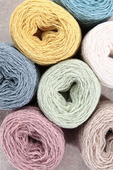 Multicolored balls of yarn for knitting. Handmade work. A set of colored cotton yarn. The concept of a hobby. Skeins of yarn for knitting as a background. Vertical photo. Top view. Copy space.